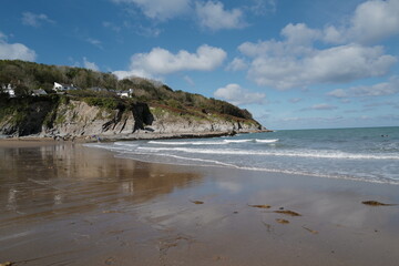 Aberporth beach on a sunny autumn day - clouds reflecting on the water on the sandy beach