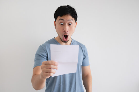 Asian man surprise and shocked by the letter in his hand on isolated background.