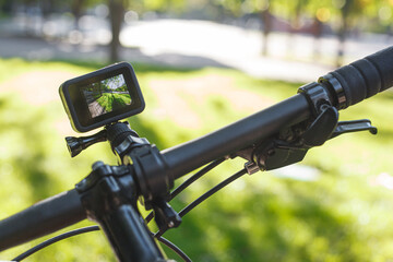 Action camera with the included screen mounted on the handlebar of a bicycle in the park