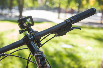 Action camera with the included screen mounted on the handlebar of a bicycle in the park
