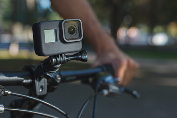 Action camera mounted on the handlebar of a bicycle that a male cyclist is holding