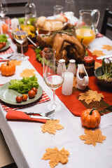 selective focus of table served with traditional thanksgiving dinner, decorated with foliage, candles and pumpkins