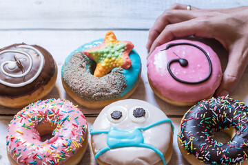 a hand picking up a donuts one of them with a handmade face mask due to the covid coronavirus pandemic.