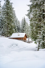 Wooden house in winter mountain landscape. Cottage / Hut in snowy mountains. Travel destination for...
