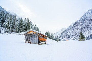 Wooden house in winter mountain landscape. Cottage / Hut in snowy mountains. Travel destination for recreation.