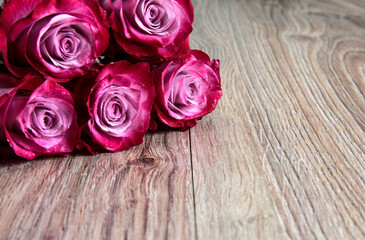 Naklejka premium 5 pink roses on a wooden background.