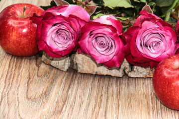 Flowers with apples on a wooden background.