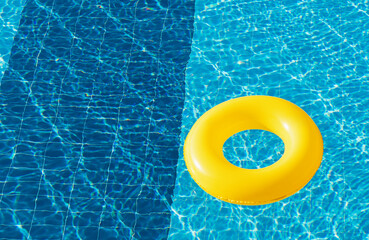 Yellow pool float, ring floating in a refreshing blue swimming pool
