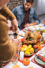selective focus of senior man opening bottle of white wine during thanksgiving celebration with family