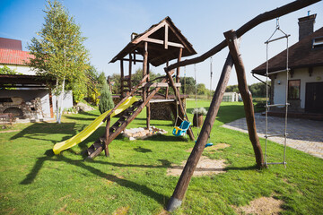 Fototapeta na wymiar Playground in the backyard with slide and swing - a place for children to play and relax