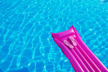 Beach summer holiday background. Inflatable air mattress, flip flops on swimming pool.