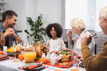 selective focus of senior woman talking to african american granddaughter during thanksgiving dinner