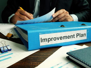 Folder with Improvement plan and working manager in office.