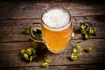 Beer mug with green hops and on a wooden table