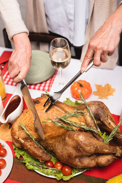 Cropped View Of Elderly Woman Cutting Tasty Turkey During Thanksgiving Celebration