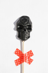black lollipop in form of skull on white background.. Creative Halloween minimal concept. flat lay top view 