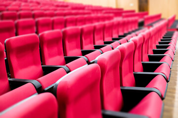 empty rows of seats of an auditorium with red reclining rows of seats and false ceiling led lights