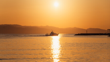Fototapeta na wymiar Golden hour view of a small yatch sailing on the beach of Marina Piccola