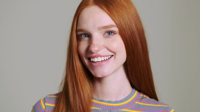 Young pretty redhead positive woman posing isolated over white wall background while winking