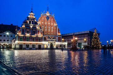 Fototapeta premium View of famous House of the Black Heads illuminated at night and Christmas tree in Riga, Latvia. Night view of Riga Town Hall Square and Roland's Statue with Christmas decoration.