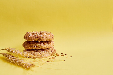 Fototapeta na wymiar Three cookies with flakes and sesame seeds and a spikelet of wheat