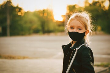 Little cute girl wearing black mask outdoors. Covid 19. School. Girl in the park in mask. - 381354406