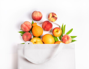 Cloth bag with fruits on white background. Fresh various fruit overflowing from a reusable cloth bag.