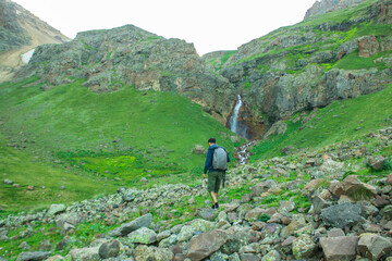 Fototapeta na wymiar two travelers climb to the waterfall