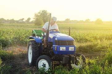 Farmer on a tractor works in farm field. Farming, agriculture. Simplify and speed up work with technology and machines. Farming and farmland. Harvesting potatoes. Harvesting potatoes in autumn.