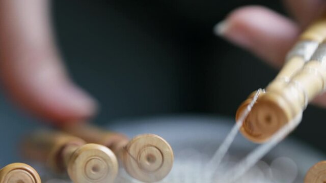 Video detail of bobbin lace handcrafting. Woman hands braiding threads to make a pattern.