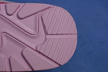 part of a sports sneaker from a pink plastic sole on a blue background