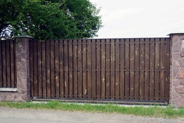 Fototapeta premium one large brown wooden gate on a rural street in green grass