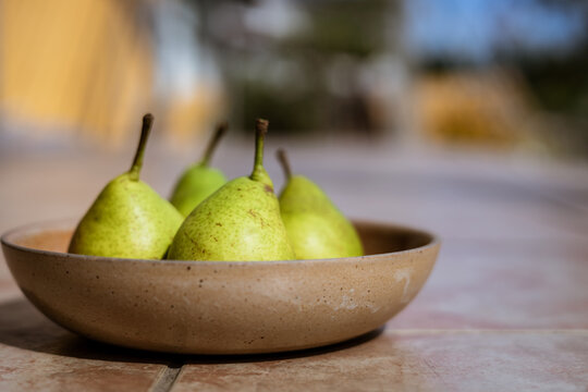 Reife grüne Birnen in einer rustikalen Schüssel auf einem Tisch im Garten. Nahaufnahme, gesunde Ernärhung.