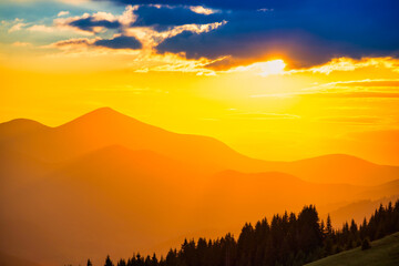 Beautiful dramatic sunset in the mountains. Landscape with sun shining through orange clouds