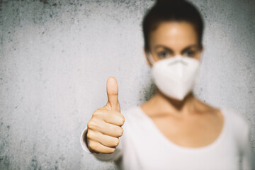 Woman with mask gesturing thumbs up.