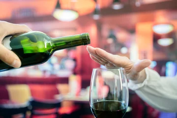 Fotobehang Woman hand rejecting more alcohol from wine bottle in bar © Brian Jackson