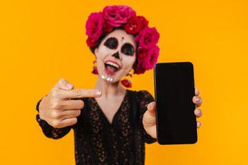 Photo of girl in halloween makeup pointing finger at mobile phone