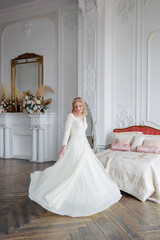 Full-length portrait of a bride in a beautiful wedding dress in the interior.