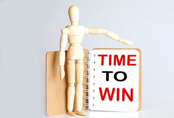 Wooden man shows with a hand to white notepad with text time to win