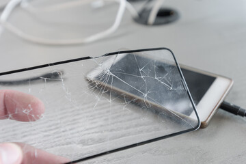 Broken protective glass on the background of charging mobile phone