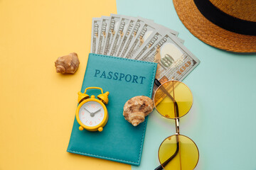 Vacation concept. Minimal simple flat lay with passport, sunglasses, hat and shell on yellow blue background. Tourist essentials