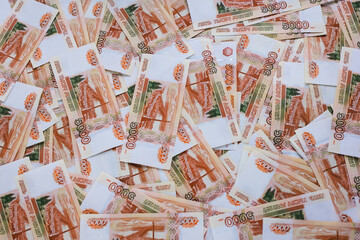 Russian money background. Rubles of five thousands denominations lie on the table mixed. Closeup. Selective focus.