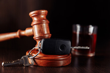 Car key, judge gavel and bottle of alcohol with glass close-up. Drinking alcohol on driving ability concept