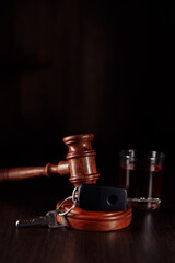 Car key, wooden judge gavel and bottle of alcohol with glass. Drink driving concept. Vertical image