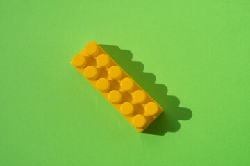 Yellow detail of children's constructor isolated on green background