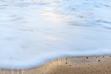 Beach in the evening with moving water which brings an effect to the surface of the sea.