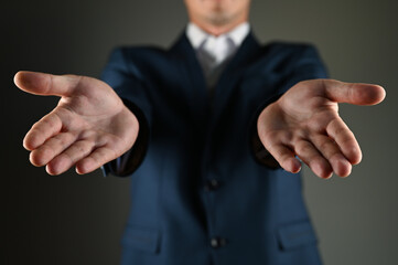 The man in the suit stretches his palms forward