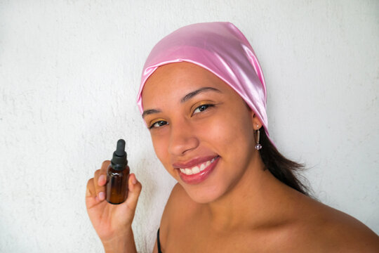 Hispanic woman with cosmetic oil in a bottle for moisturizing facial skin care