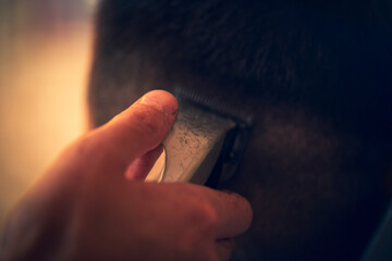 Close up of hand holding professional electric trimmer at barber shop.