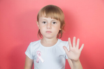 Little girl in white t-shirt with breast cancer warning ribbon showing stop sign